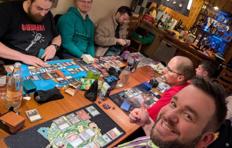 Eine Gruppe Menschen sitzt gemeinsam an einem Tisch und Spielt Magic The Gathering in geselliger Runde